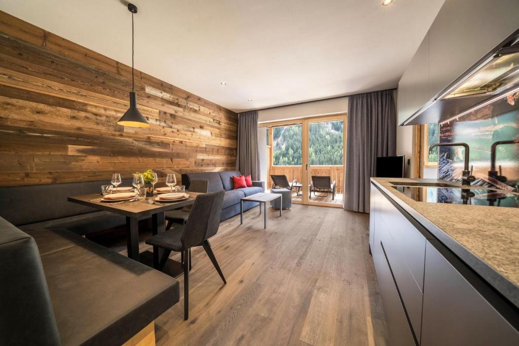 a kitchen and living room with a wooden wall at Seebrunn - Kaserfeld Alm in Ultimo