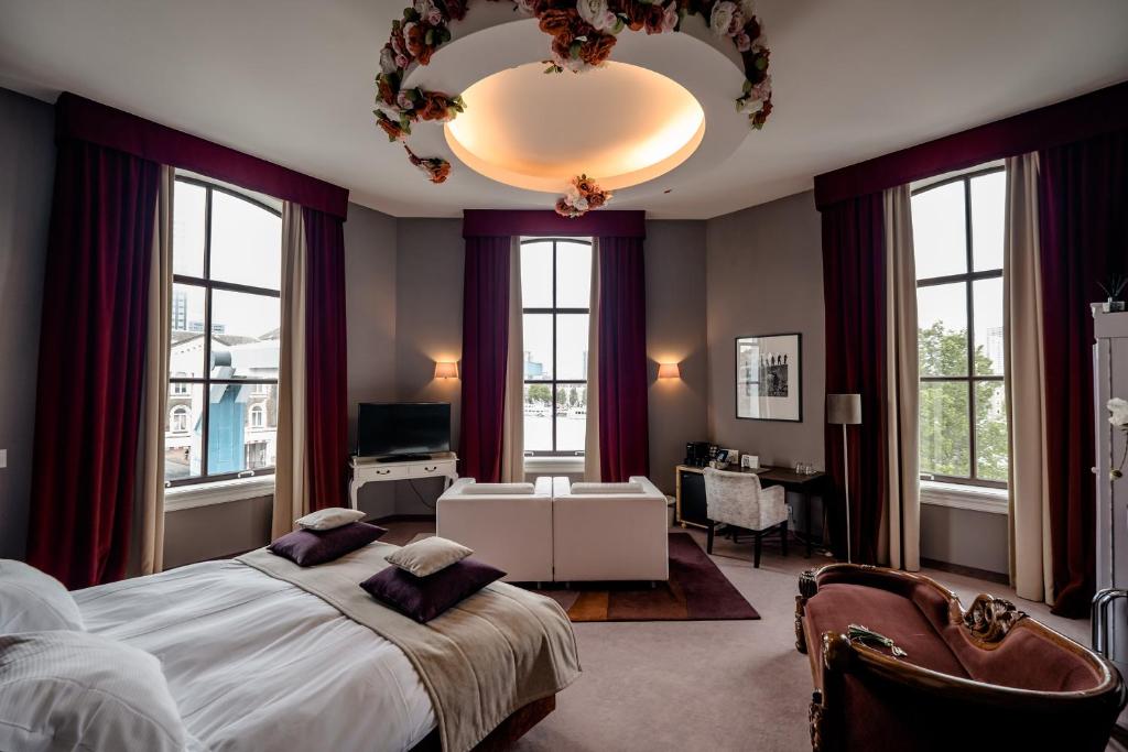 a bedroom with a large bed and a chandelier at Suitehotel Pincoffs in Rotterdam