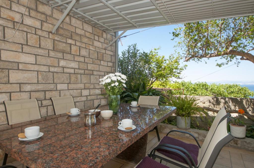 um pátio com paredes de pedra, uma mesa e cadeiras em Apartments Mira em Splitska