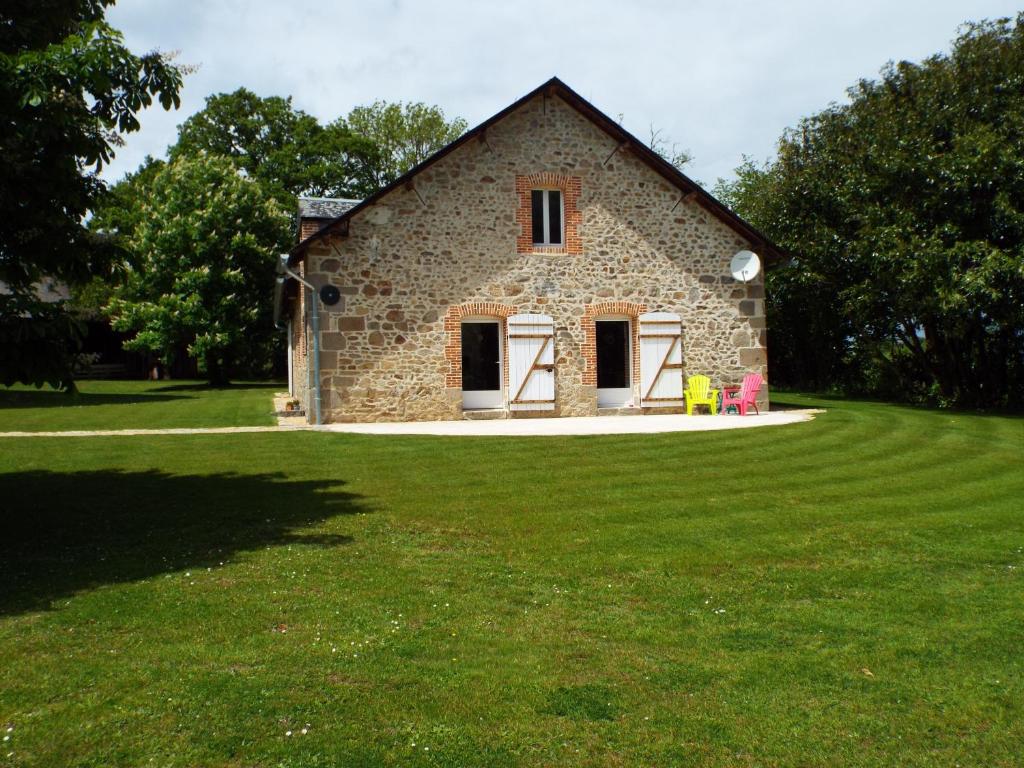 kamienny dom na polu zielonej trawy w obiekcie Gîte La Peyre w mieście Le Grand-Bourg