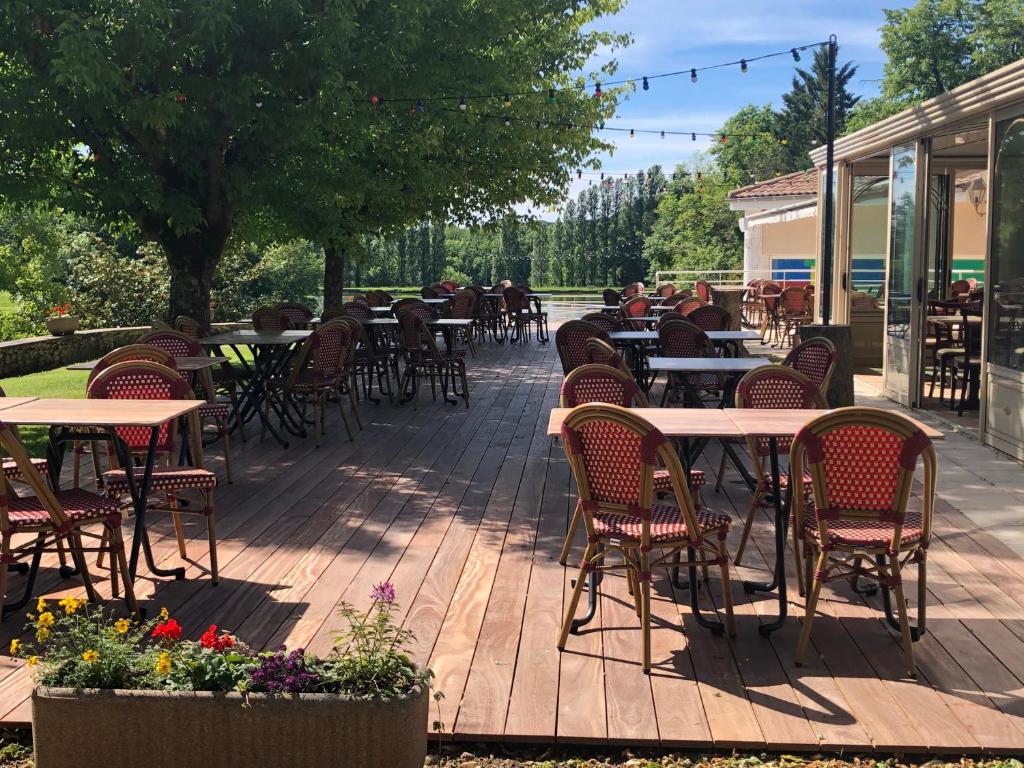 a patio with tables and chairs on a deck at Hotel Restaurant La Dame du Lac in Monflanquin