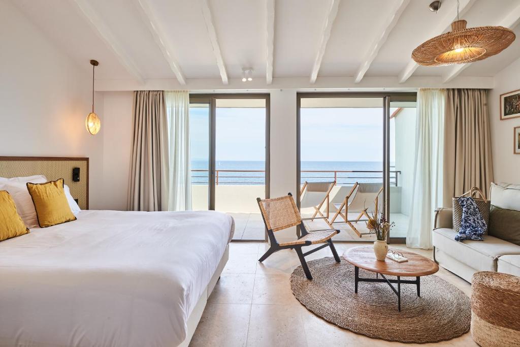 a bedroom with a bed and a living room with the ocean at Les Roches Brunes in Collioure