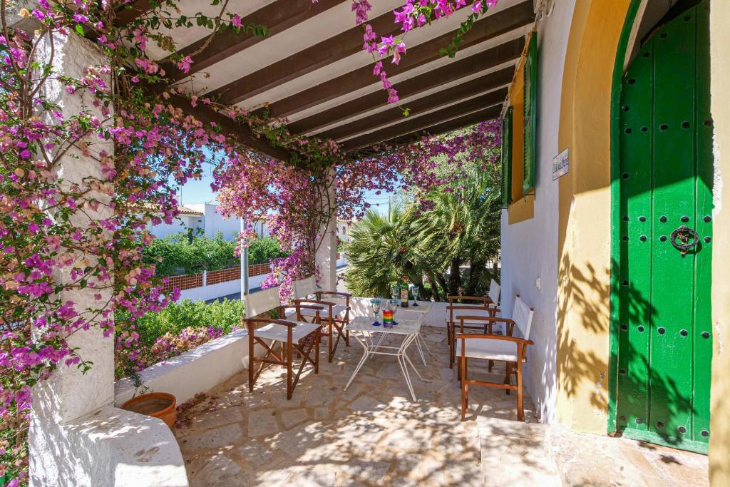 um pátio com mesas, cadeiras e flores roxas em Chateau Mahe em Port d'Alcudia
