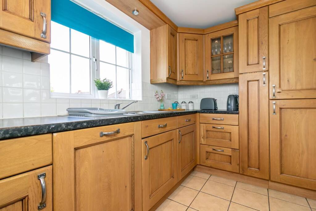a large kitchen with wooden cabinets and a window at Cunningham Lodge in Hatfield