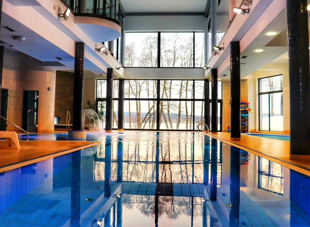 a large swimming pool with blue tiles in a building at Pirat Hotel & SPA-hotel z basenem in Olsztyn
