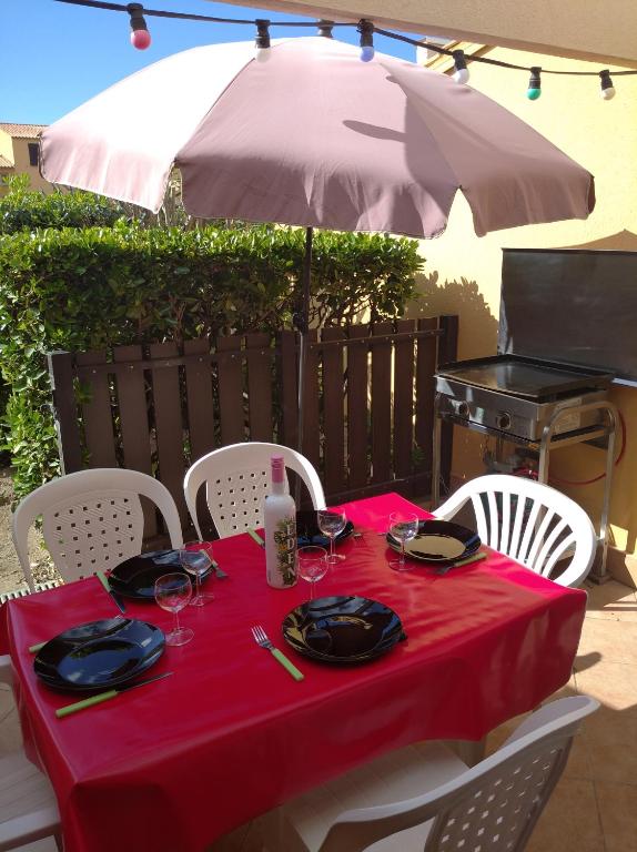 une table avec un chiffon de table rouge et un parasol dans l'établissement Résidence le Neptuna 50 mètres plage réservation du samedi au samedi en haute saison, au Cap d'Agde