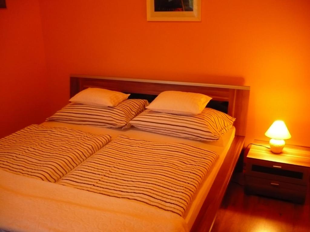 Cama en habitación con pared de color naranja en Delfin Apartman, en Sárvár