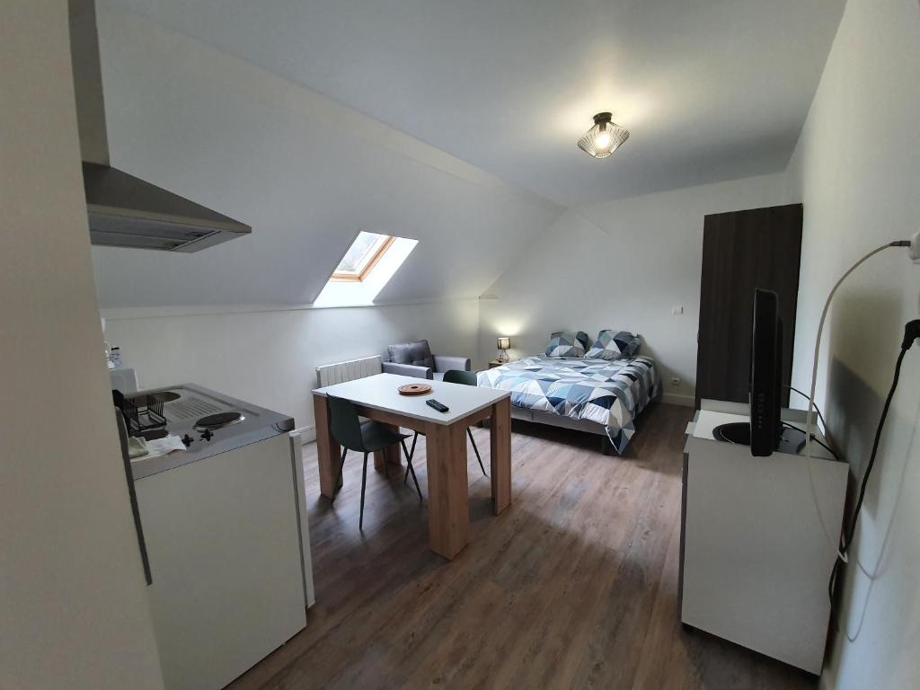 ein kleines Zimmer mit einem Bett und einem Tisch sowie einer Küche in der Unterkunft Appart'Ardennes 3 in Vireux-Molhain