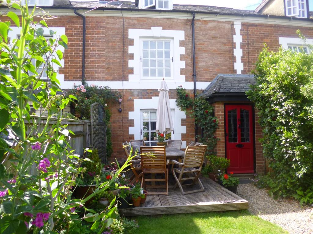 un patio con mesa y sillas frente a una casa en Cranberry Cottage en Wallingford