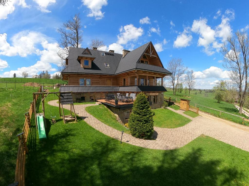 a large wooden house with a playground in the yard at Galicówka na Górce in Biały Dunajec