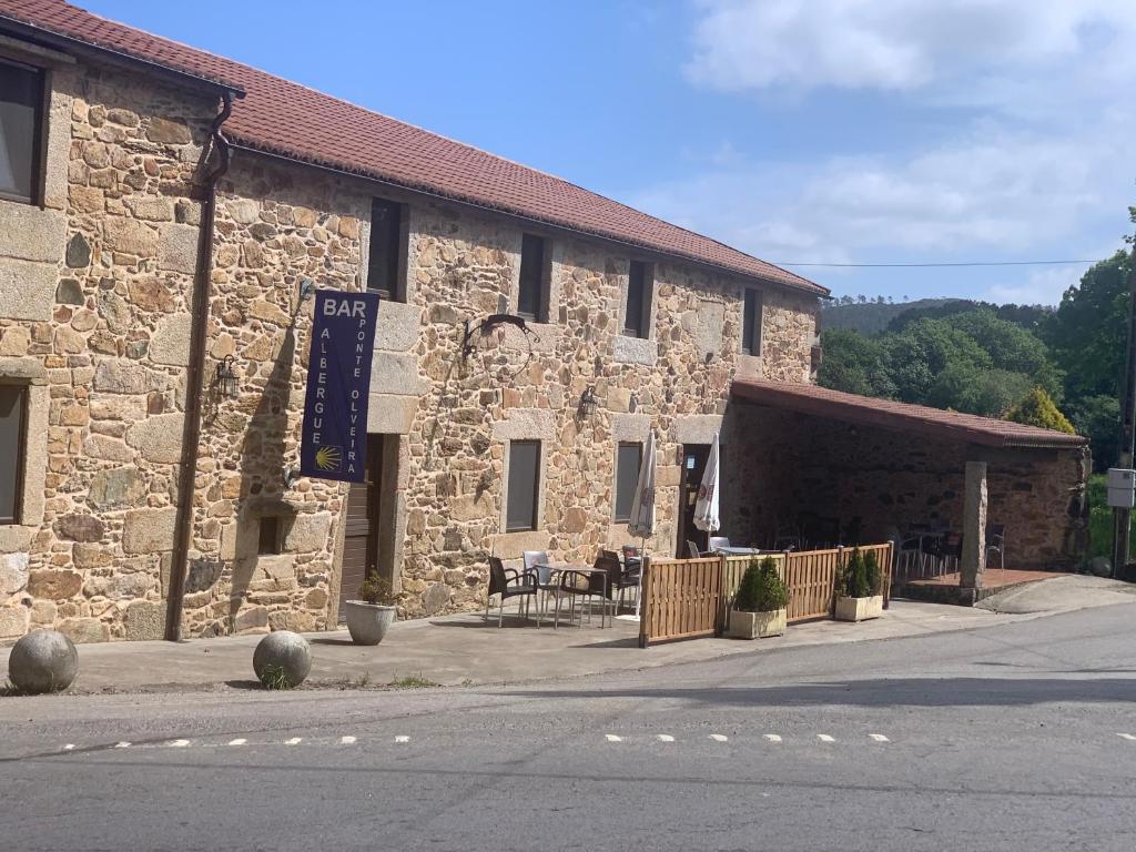 a large stone building with a table in front of it at Albergue Ponte Olveira in Mazaricos