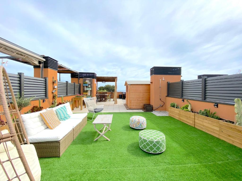 une terrasse avec de l'herbe verte, un canapé et des chaises dans l'établissement Coma-Ruga Beach Apartment, à Tarragone