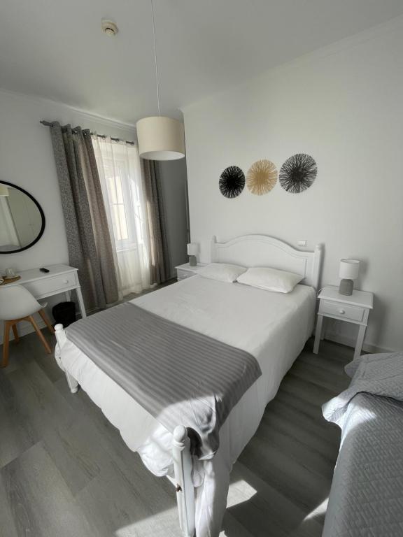 a white bedroom with a large bed and a desk at Casa de Hospedes D. Maria Parreirinha in Sintra