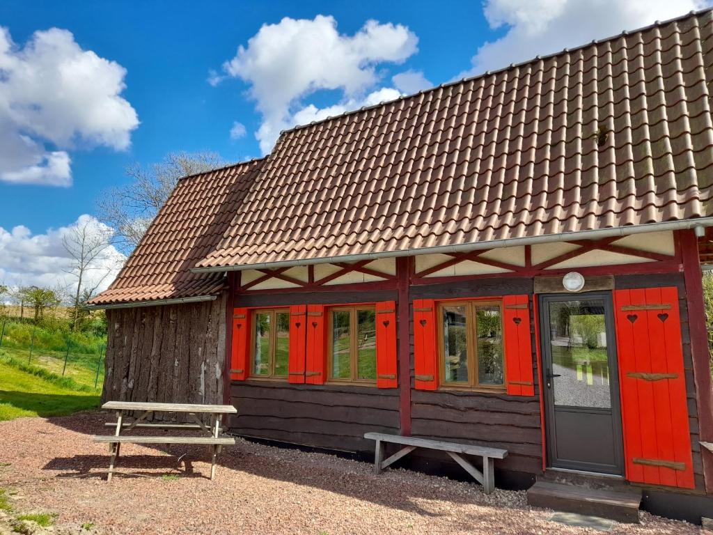 a small building with red doors and a bench at Holiday village in Réclinghem