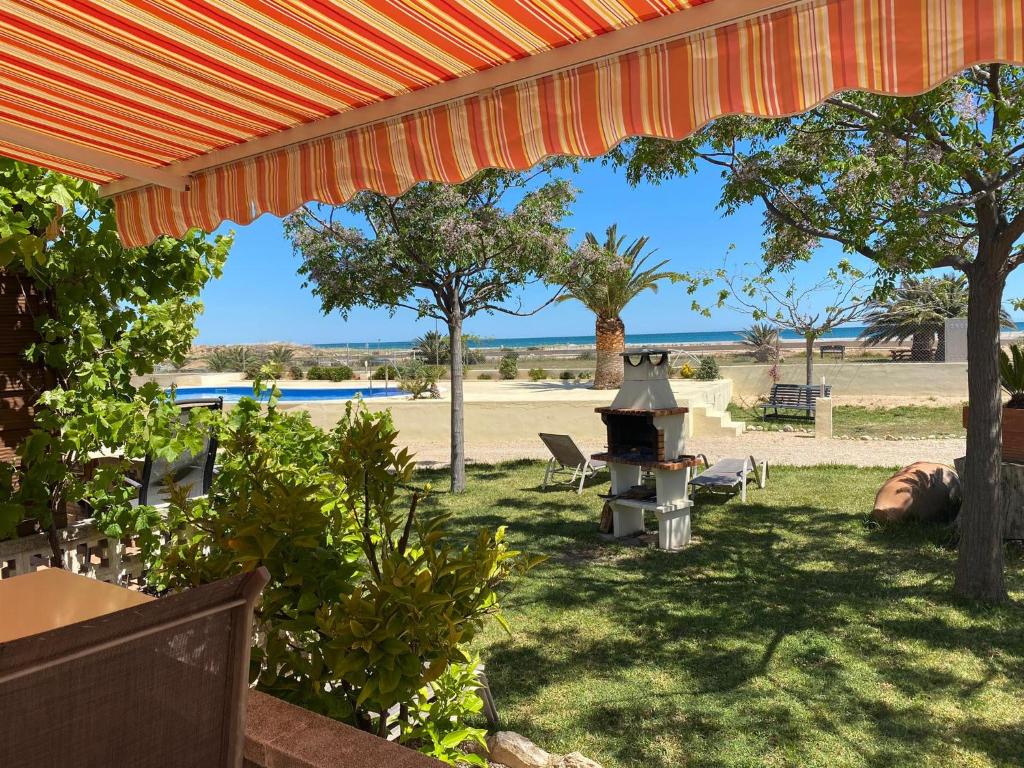 un patio trasero con una parrilla, árboles y una playa en Beach Resort La Margarita, en Hospitalet de l'Infant