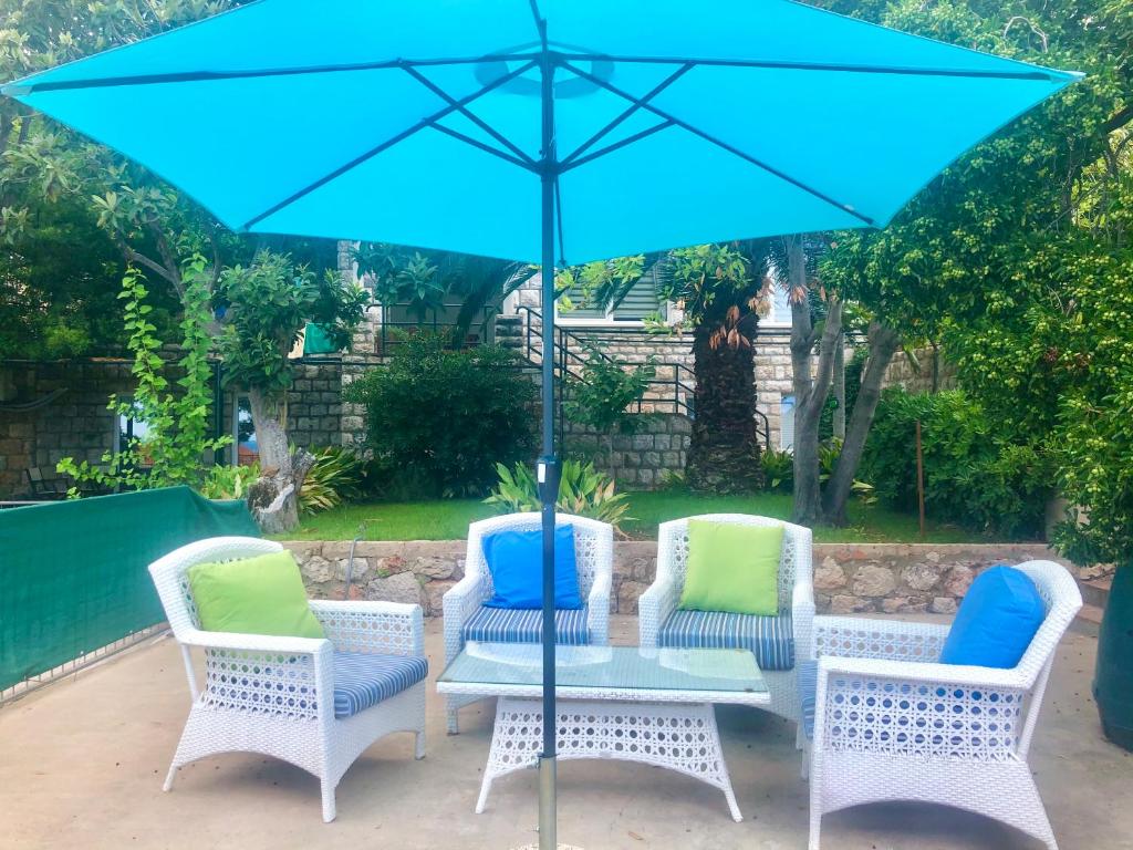 una mesa con sillas y una sombrilla en el patio en Ida Apartments en Dubrovnik