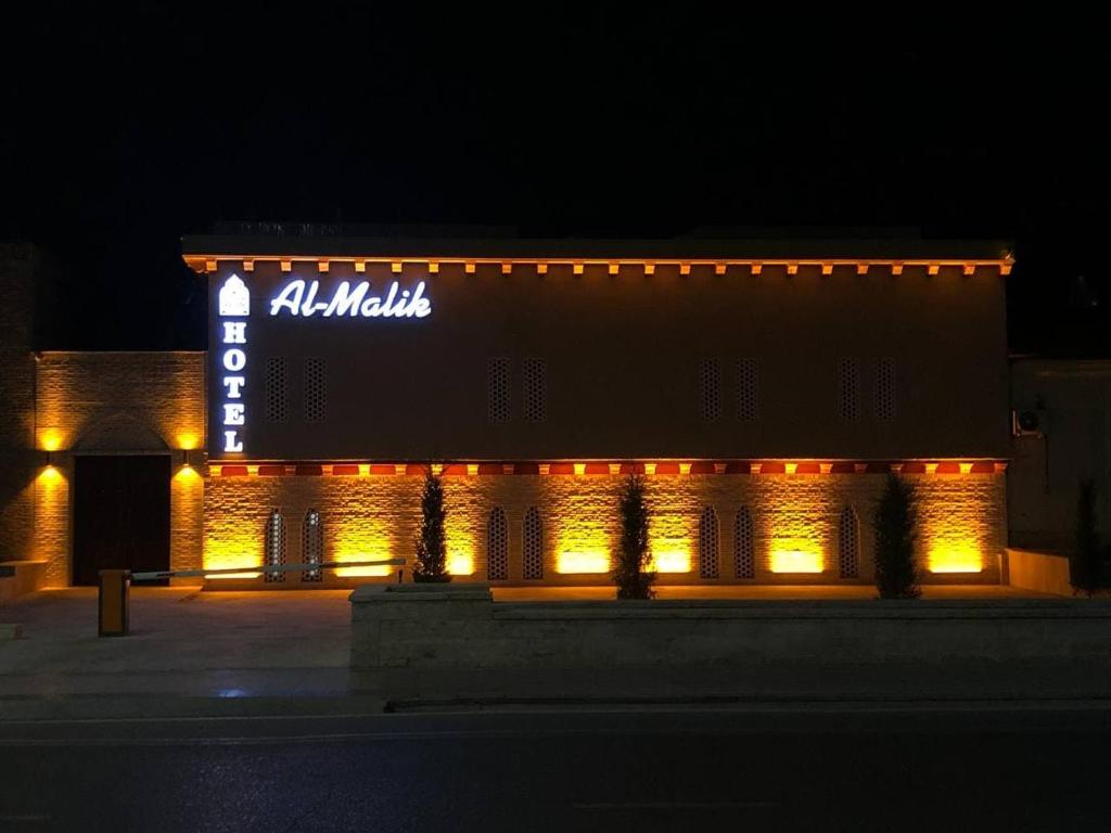 a building with a sign on the side of it at night at AL-MALIK Boutique Hotel in Bukhara