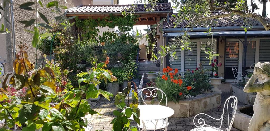 un jardín con 2 sillas y flores frente a una casa en Maison d'Hôtes et Roulotte" Le 6 Bis", en Romans-sur-Isère