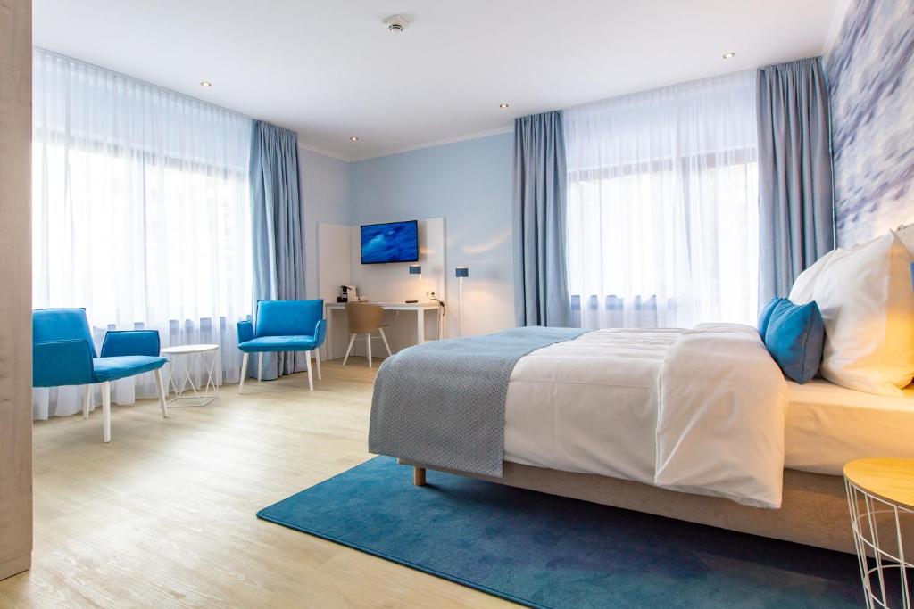 a bedroom with a large bed and blue chairs at Stratmanns Haus am See in Lembruch