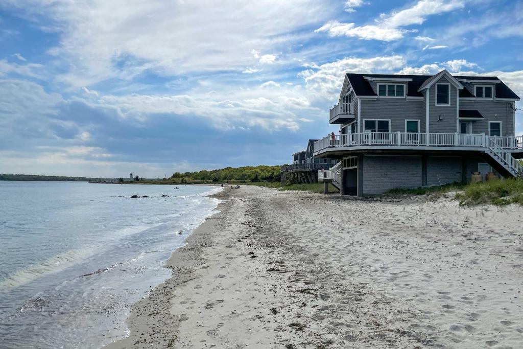 a house on the beach next to the water at Sunny Beach House Getaway - Steps From Water! in Mattapoisett