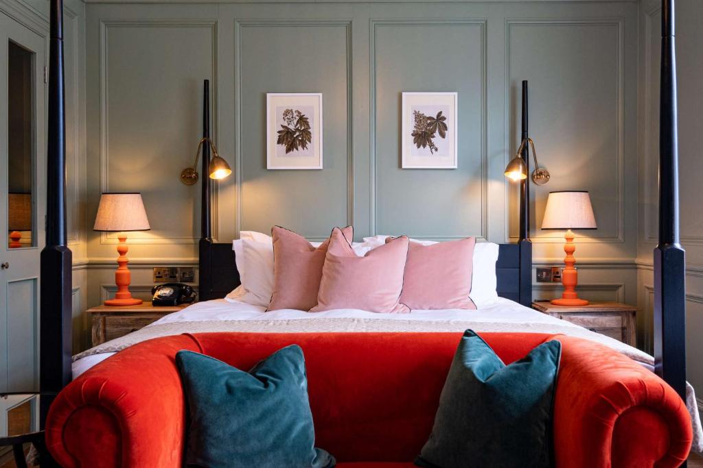 a bedroom with a bed with a red couch and two lamps at The Canford in Poole