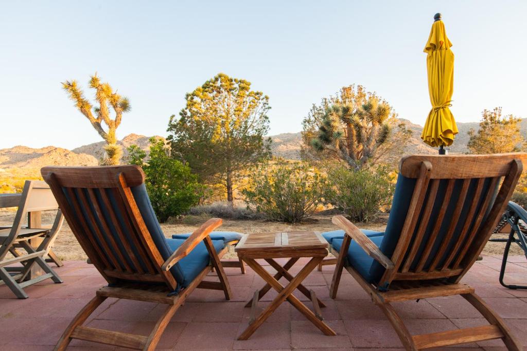 twee stoelen en een tafel en een parasol op een patio bij @ Marbella Lane - 10 Acres Oasis Desert Retreat! in Joshua Tree