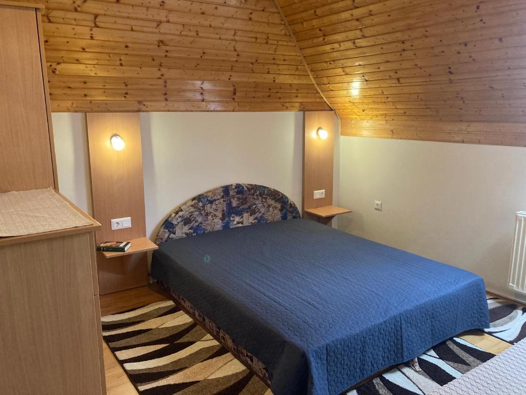 um quarto com uma cama azul e um tecto de madeira em Szőlőskert Apartman em Cserszegtomaj