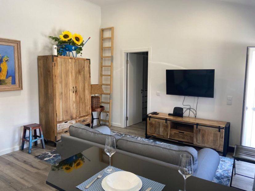 een woonkamer met een bank en een flatscreen-tv bij Casa do Chinelo Azul in Queluz