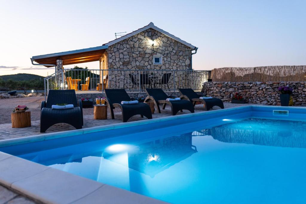 - une piscine avec des chaises et une maison dans l'établissement Holiday home - Villa Juli, à Šibenik