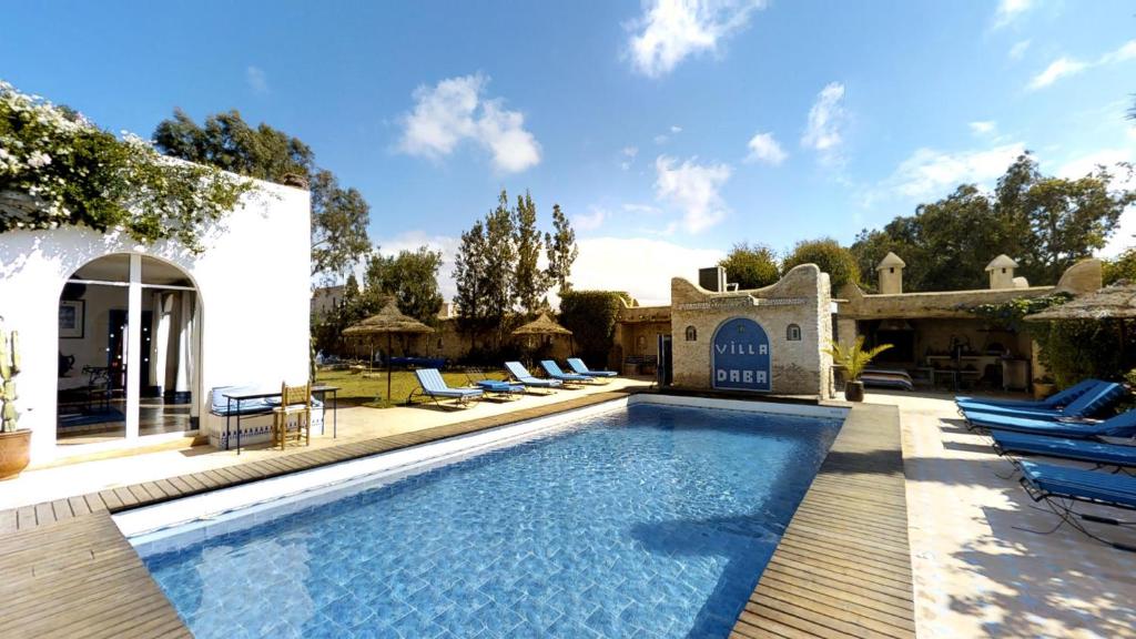 a swimming pool with lounge chairs next to a house at Villa Daba in Ghazoua