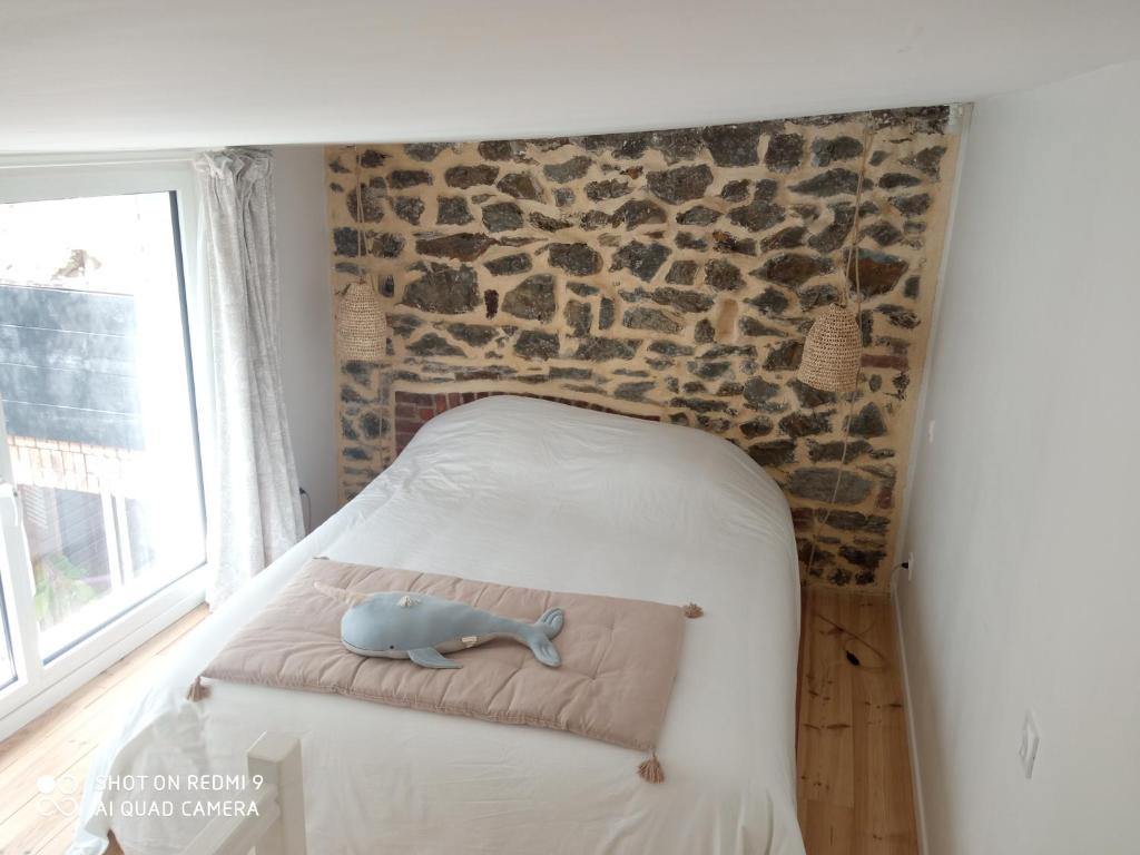 Dormitorio pequeño con cama con pared de piedra en Charmant logement T2 à 2 pas de la mer, en Granville