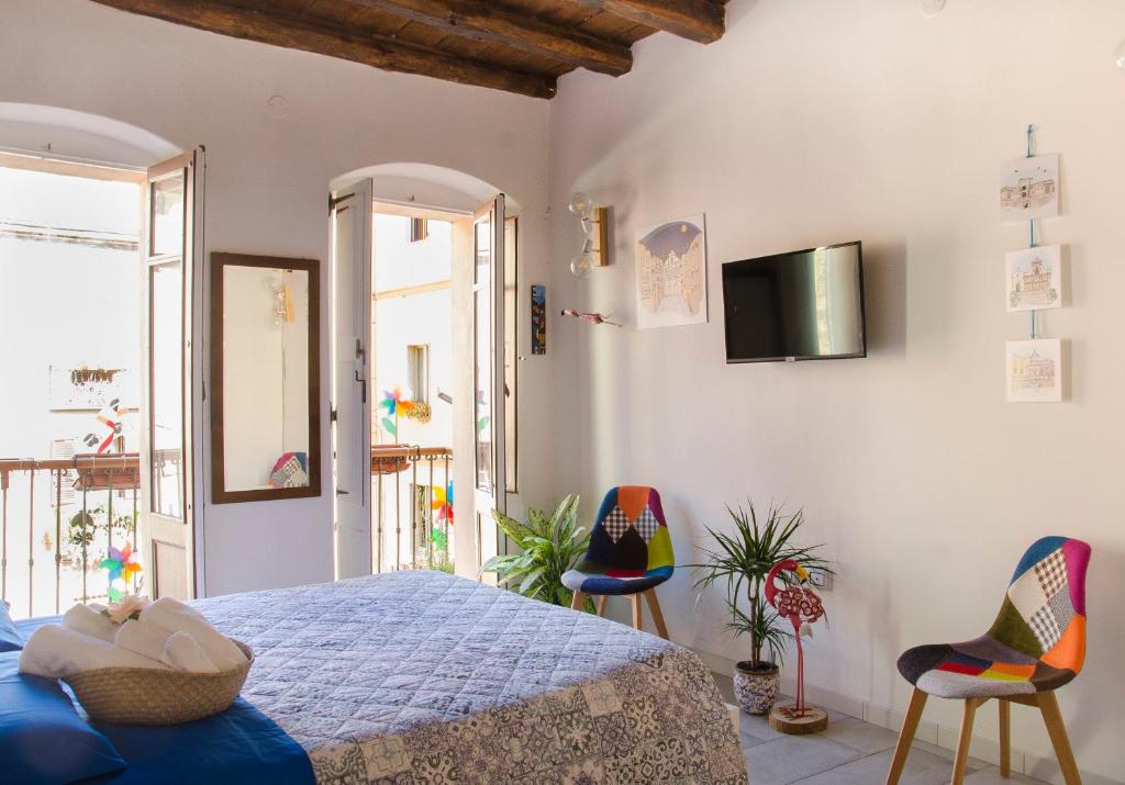 1 Schlafzimmer mit einem Bett und 2 Stühlen sowie einem TV in der Unterkunft Domu 'e Casteddu in Cagliari