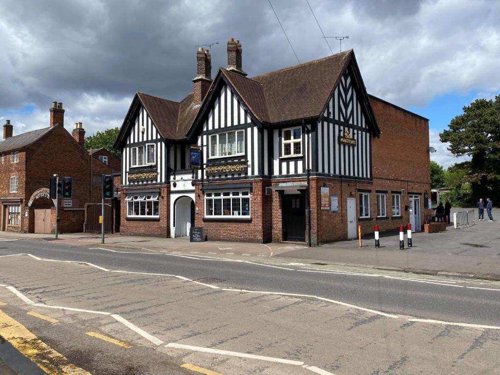 a black and white building on the corner of a street at The Plough Inn Wigston in Wigston Magna
