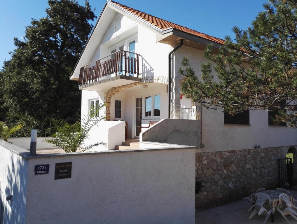 a white house with a balcony on top of a wall at Risika Apartmani in Risika