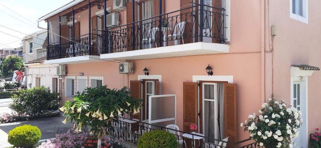 a pink building with balconies and flowers on a street at Apartments Elena in Kavos