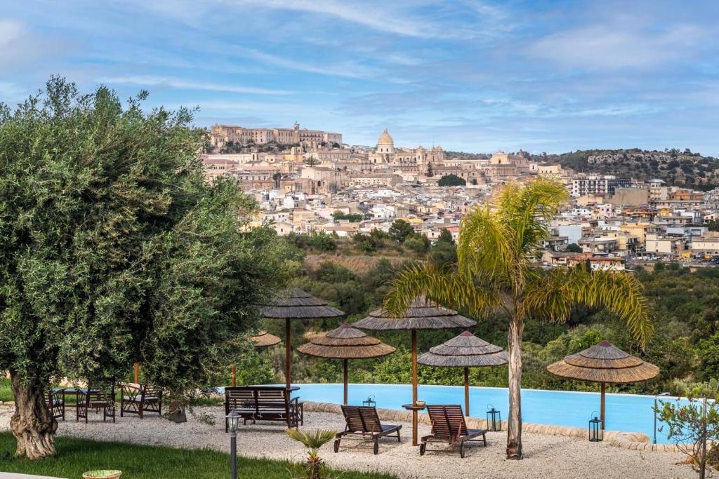 um grupo de cadeiras e guarda-sóis ao lado de uma piscina em Baglio Genovesi em Noto