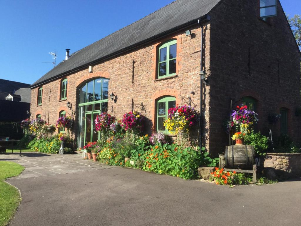 um edifício de tijolos com flores à frente em The Bees Knees @ Redhill Grange em Monmouth