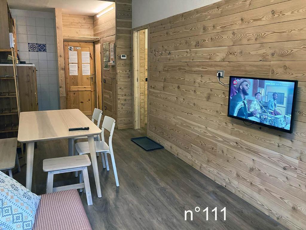 a room with a table and a tv on a wall at House Cervinia Apartments in Breuil-Cervinia