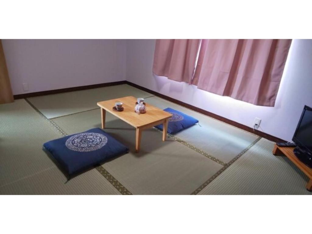 a room with a table and two ottomans at Guest House Fukuchan - Vacation STAY 34479v in Kaiyo