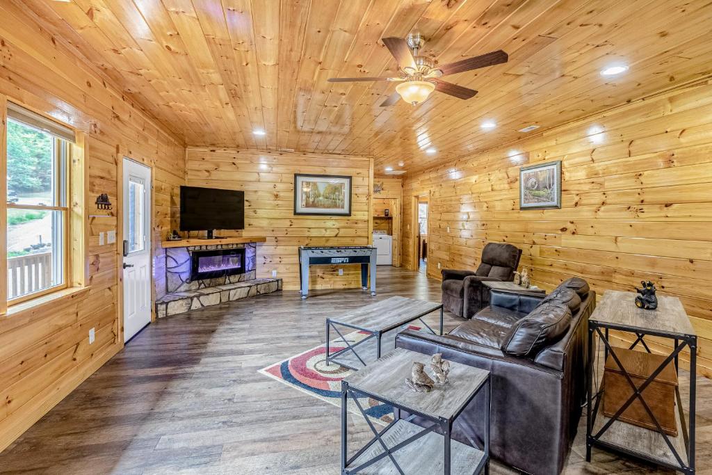 a living room with a ceiling fan and a tv at Hilltop Cabin in Bryson City