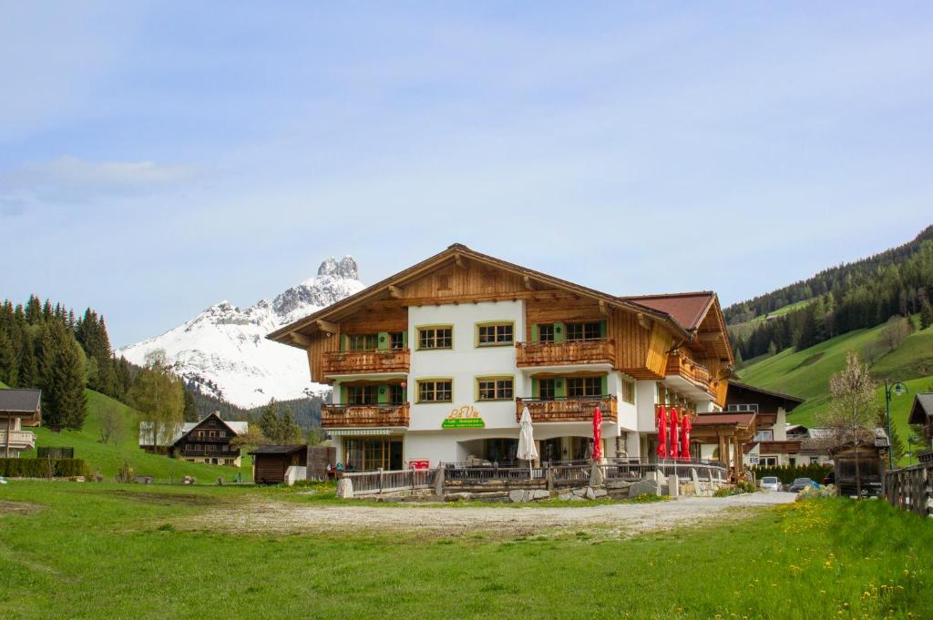 a large building in a field with a mountain at Ferienwohnung "Mein Alpenjuwel" in Filzmoos