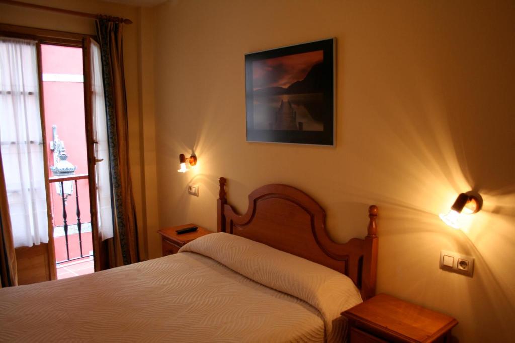 - une chambre avec un lit et une photo sur le mur dans l'établissement Pensión Argüelles, à Ribadesella
