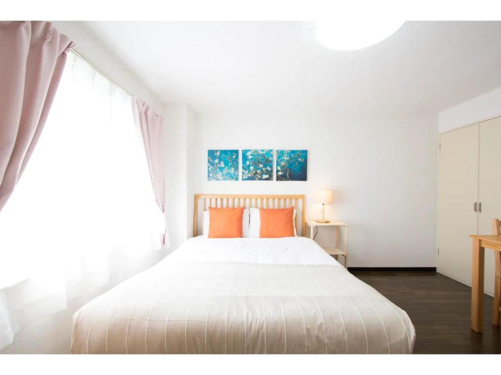 a white bedroom with a large bed with orange pillows at Haimu Shanzerize 7,12 - Vacation STAY 11296 in Sapporo