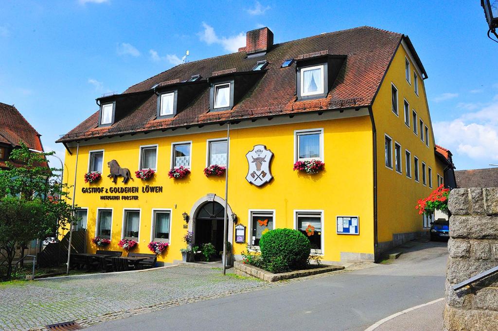 un bâtiment jaune avec un toit brun dans l'établissement Landgasthof Zum goldenen Löwen, à Moosbach