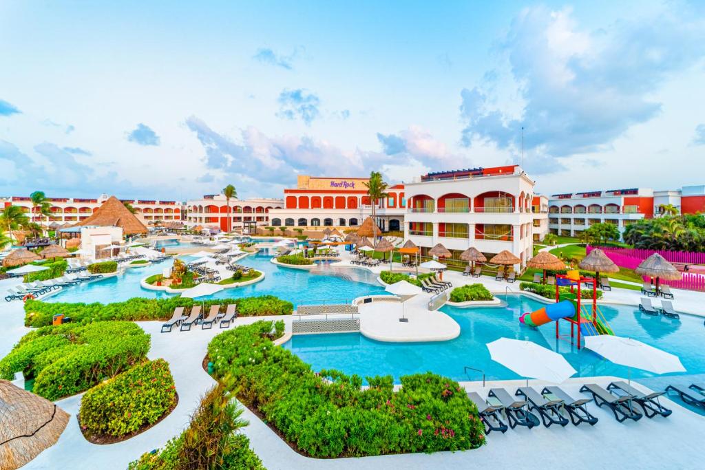 un complejo con piscina con sillas y parque infantil en Hard Rock Hotel Riviera Maya - Hacienda All Inclusive, en Puerto Aventuras