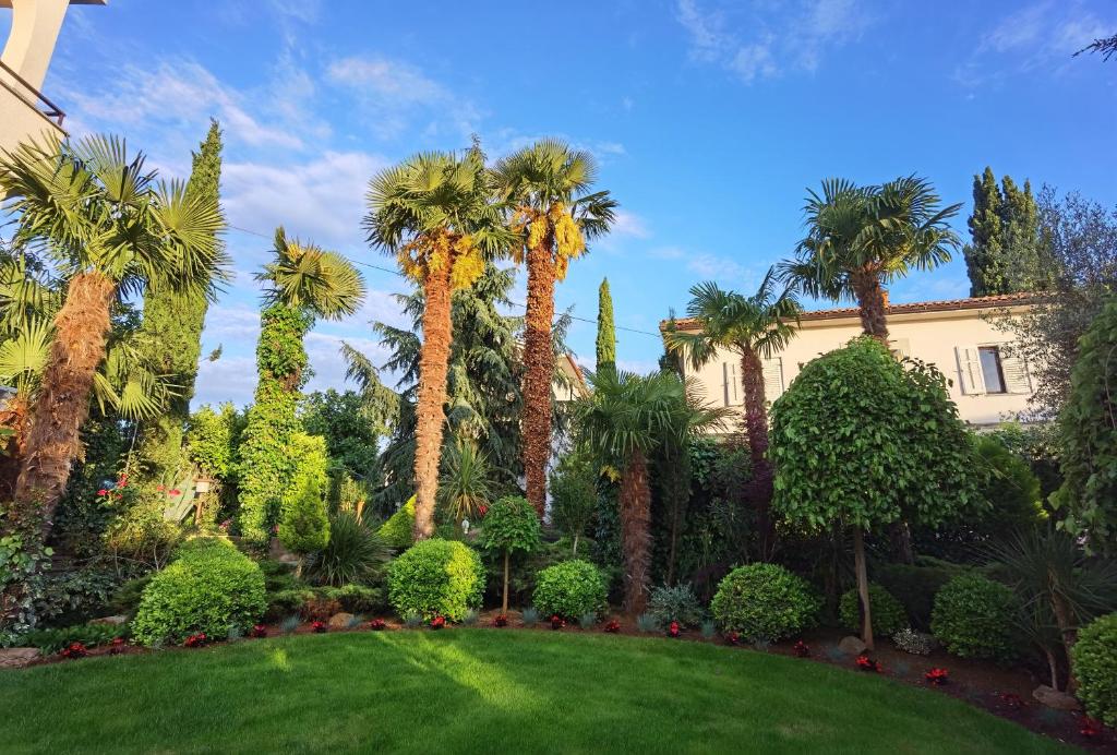 um jardim com palmeiras e uma casa em Apartment Skaline em Malinska