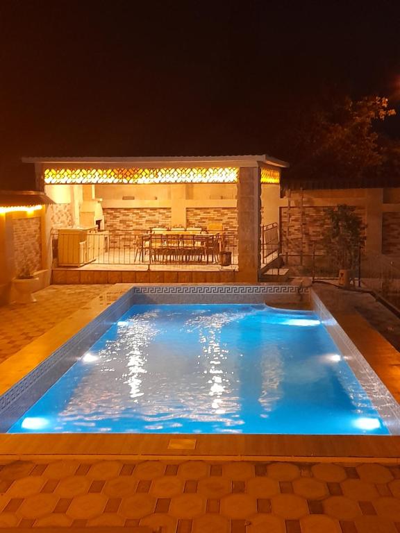a swimming pool at night with a restaurant in the background at Raffles Villa with pool in Gabala