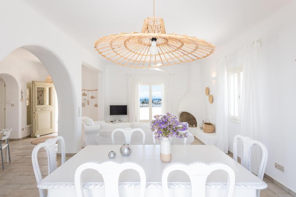a white dining room with a white table and white chairs at Irene's House in Aliki in Aliki