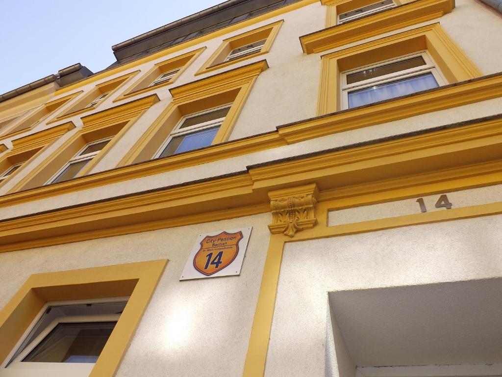 包岑的住宿－City-Pension-Bautzen，黄色的建筑,旁边标有标志