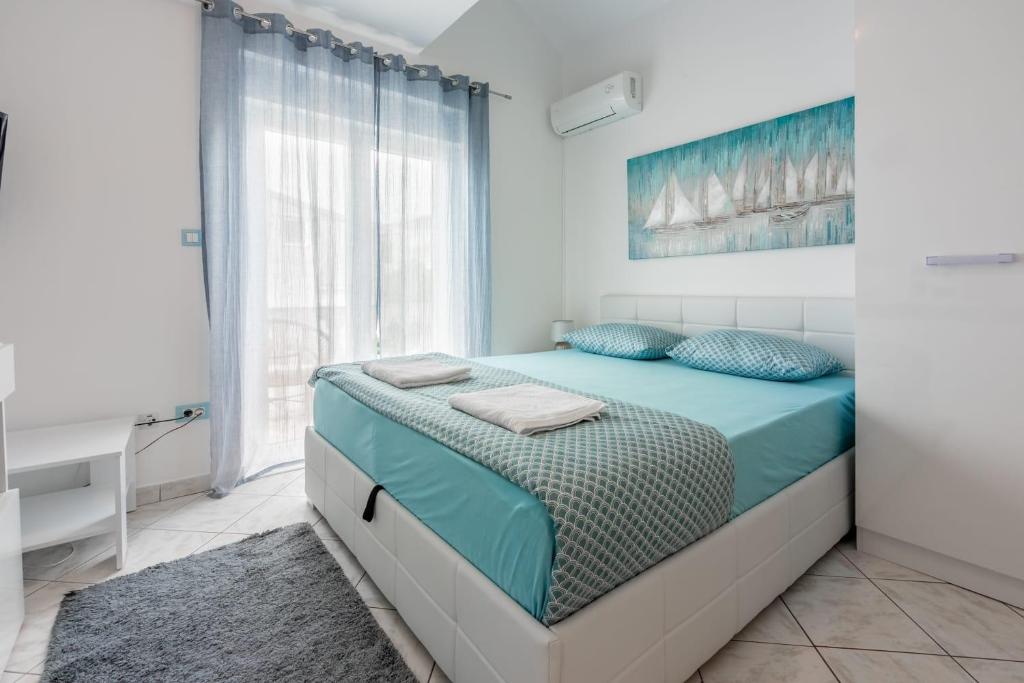 a bedroom with a bed with blue pillows and a window at Apartmani Tena in Selce